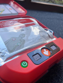Defibrylator HeartSave AED z szafką i oznakowaniem